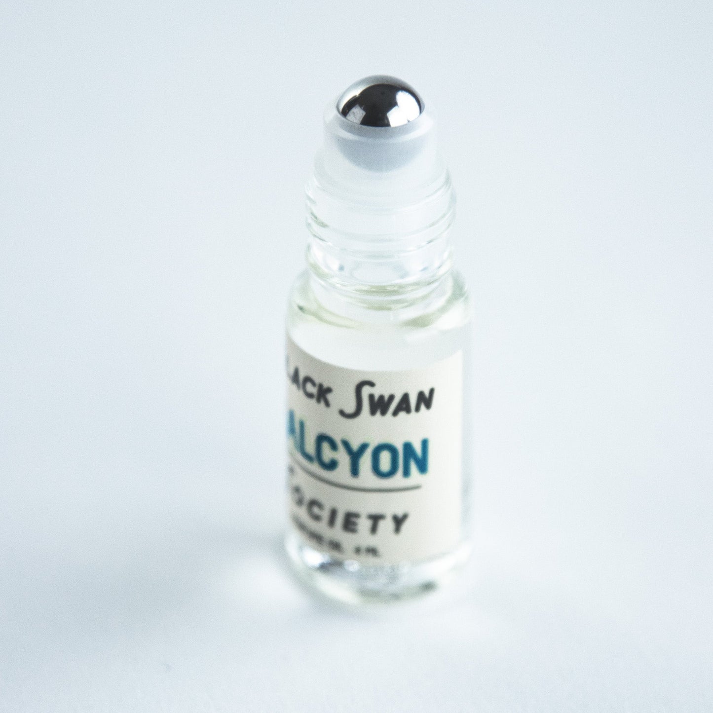Perfume Oil Rollerball bottle with the roller exposed it has the label Black Swan Society Halcyon 4ml